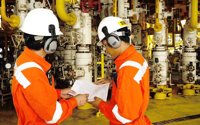 AW Associates LLP Factory machine operators with ear protectors and hard hats with hi vis overalls.